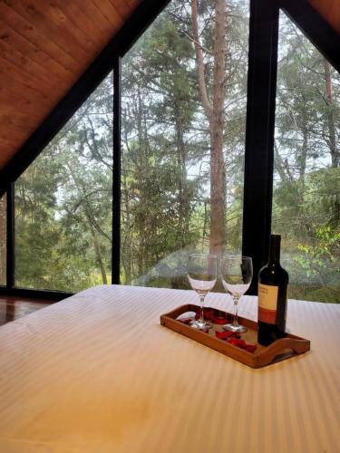 a bottle of wine and two glasses on a bed at Cabaña Onix - La Pascana Ecolodge in Mazo
