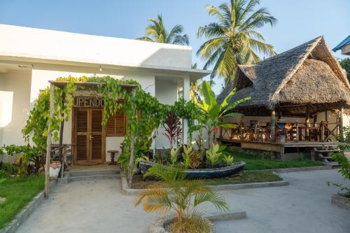 a resort with a restaurant with a thatch roof at Coconut Mafia Island Bungalows in Utende