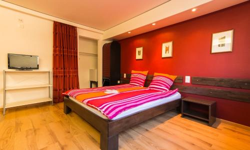 a bedroom with a bed with a red wall at Metropol in Biel