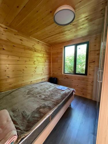 a large bed in a wooden room with a window at Jyrgallifе in Darkan