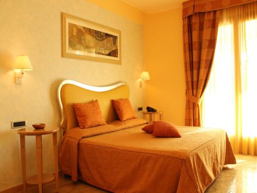 a bedroom with a bed with orange sheets and a window at Blu Tropical Resort in Zambrone