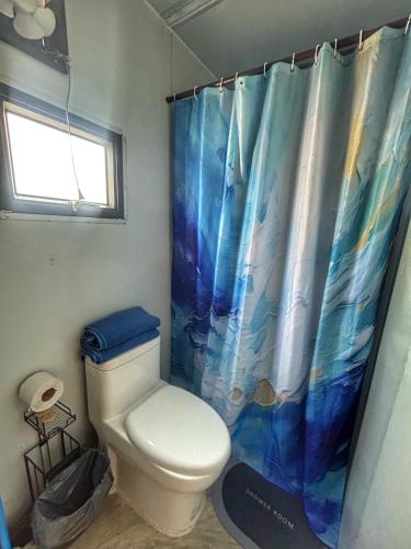 a bathroom with a toilet and a shower curtain at Casa Faro cerca de la playa in Barra de Navidad