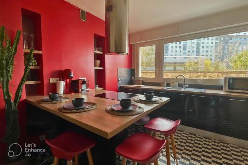 - une cuisine avec une table en bois et des murs rouges dans l'établissement La Parenthèse Rennaise, à Rennes