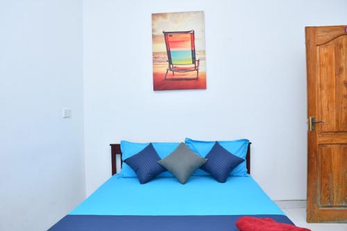 a bedroom with a blue bed with a colorful chair at Lailaguest in Trincomalee