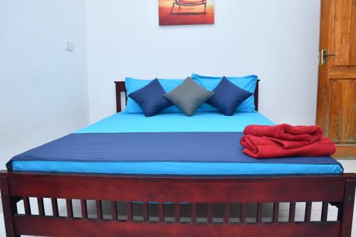 a bed with blue sheets and red towels on it at Lailaguest in Trincomalee