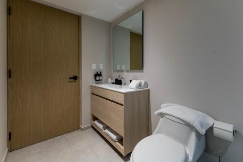 a bathroom with a toilet and a sink and a mirror at Capitalia Hipodromo Condesa in Mexico City