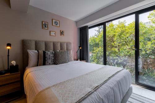 a bedroom with a large bed and large windows at Capitalia Hipodromo Condesa in Mexico City