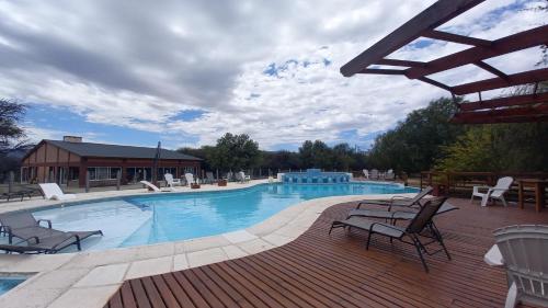 a large swimming pool with chairs and a wooden deck at El Principio Palace in Villa Cura Brochero