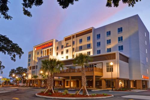 a hotel with palm trees in front of it at Hilton Garden Inn Biloxi in Biloxi