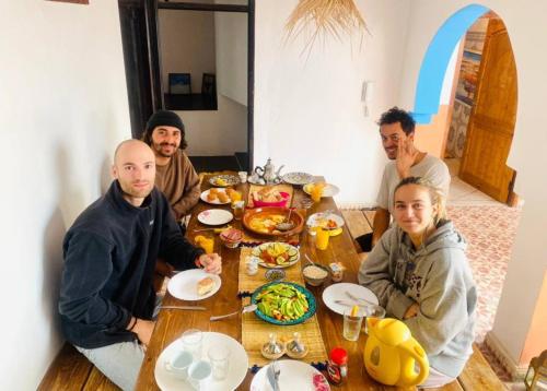 een groep mannen die rond een tafel eten bij Binic surf house in Agadir
