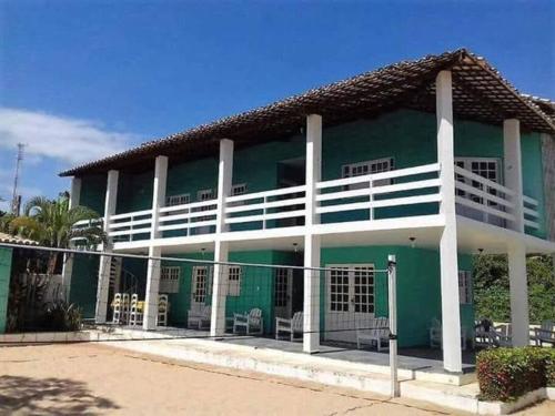ein grünes Gebäude mit weißen Säulen in der Unterkunft Casa na Barra de São Miguel in Barra de São Miguel