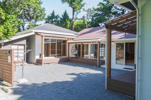 a home with a porch and a building at Guesthouse TOMARITOMARO in Shikineshima