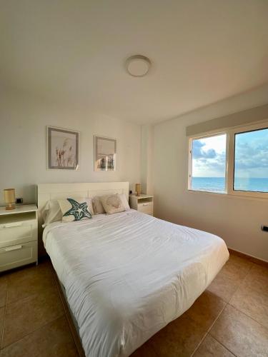 a bedroom with a large white bed and a window at OceanView Apartment in La Manga del Mar Menor