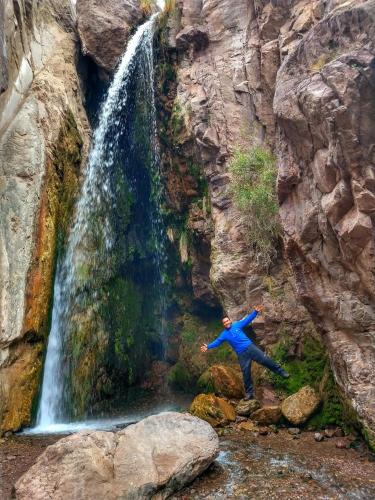 a man standing on rocks in front of a waterfall at Cabaña Rincón del Sol in Potrerillos