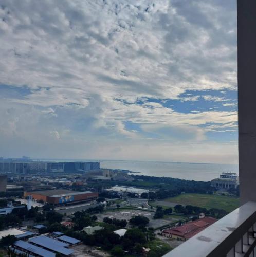 a view of a city with the ocean in the background at De Luxe, Standard and Studio Suites -The Breeze Residences-close to Airport,Mall of Asia, US Embassy in Manila