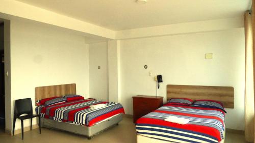 a bedroom with two beds and a chair at Camber Inn in Máncora