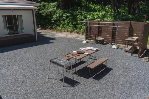 a picnic table and a bench in a yard at Guesthouse TOMARITOMARO in Shikineshima