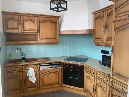 a kitchen with wooden cabinets and a sink at Ch'tite Maison, Bienvenus à Vous! in Altrippe