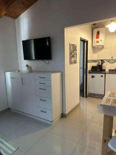 a living room with a tv on the wall and a kitchen at Lo de Hugo in Muñiz