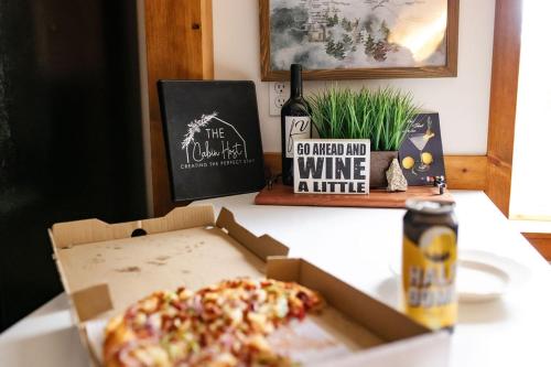 a pizza in a box on a table with a bottle of wine at Buckeye Bear's Den-ac-walking Distance To Town in Shaver Lake
