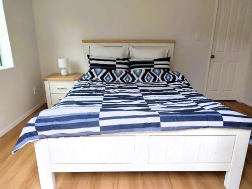a white bed with a blue and white striped comforter at Two bedroom homestay with private entrance in convenient location in Auckland