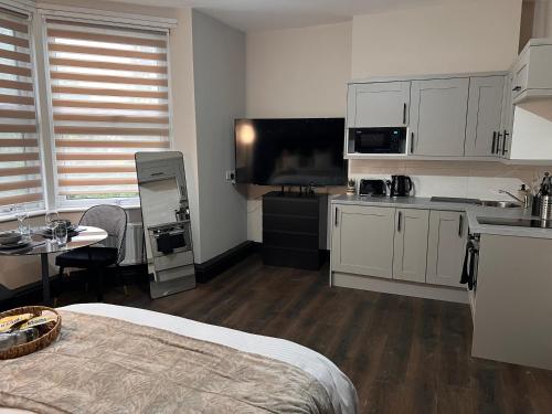 a room with a bed and a kitchen with a table at King Size Studio Apartment Streatham in London