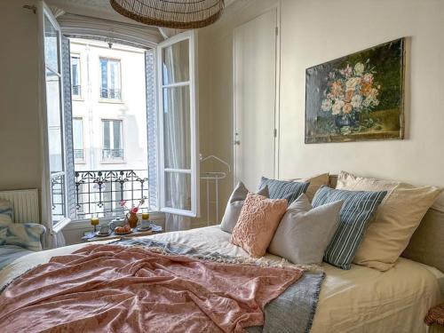 une chambre avec un lit avec des oreillers et une fenêtre dans l'établissement Chic entre Histoire et Modernité, à Paris
