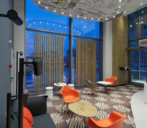 a room with orange chairs and tables and windows at Ibis Konya in Konya