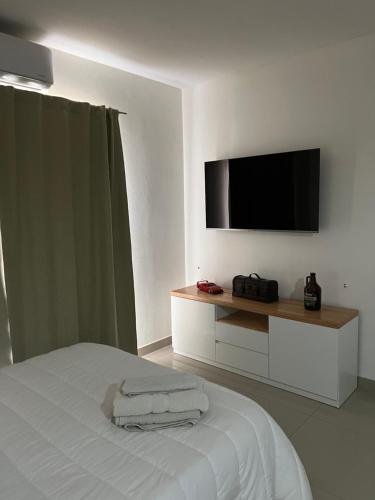 a white bedroom with a flat screen tv on the wall at Lo de Hugo in Muñiz