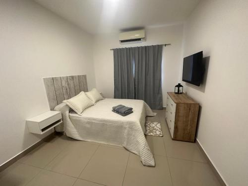 a small bedroom with a bed and a television at Lo de Hugo in Muñiz