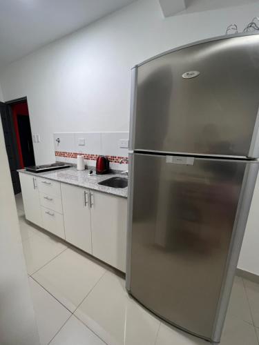 a stainless steel refrigerator in a kitchen with white cabinets at Lo de Hugo in Muñiz