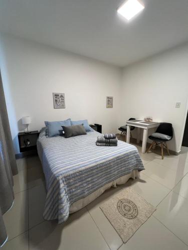 a white bedroom with a bed and a table at Lo de Hugo in Muñiz