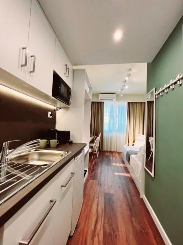 a kitchen with white cabinets and a green wall at 70 steps studio B in Thessaloniki