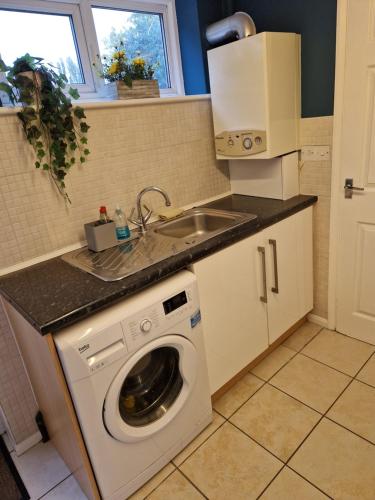 a kitchen with a washing machine and a sink at Cozy flat & Lovely garden, High Speed WiFi in Cranford