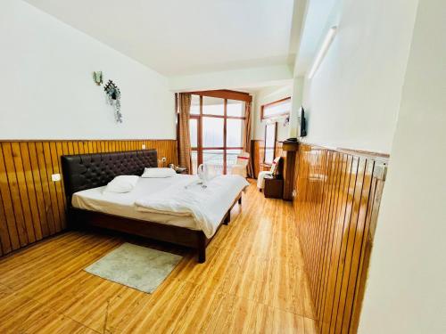 a bedroom with a bed and a wooden floor at Hotel Tashi Gyal Tsen in Pelling