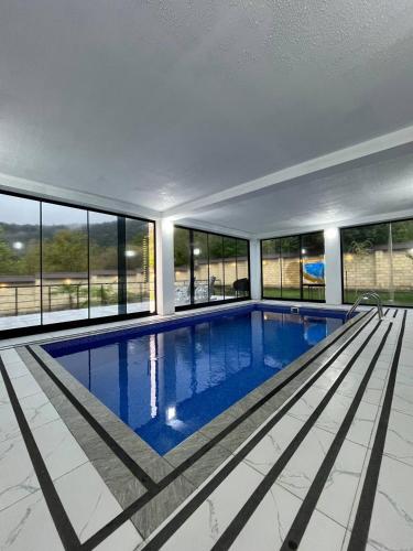 a large swimming pool in a building with windows at Qafqaz Mountain Terrace İndoor Hot Pool in Gabala