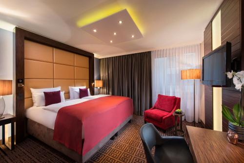 a hotel room with a large bed and a red chair at Hotel Palace Berlin in Berlin