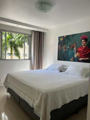 a bedroom with a large bed with a painting on the wall at Top Floripa Apartment in Florianópolis