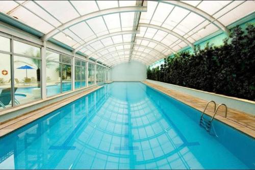 a swimming pool with a glass ceiling and an indoor swimming pooliteratorhaarhaarhaar at Apartamento lindo com garagem in Sao Paulo