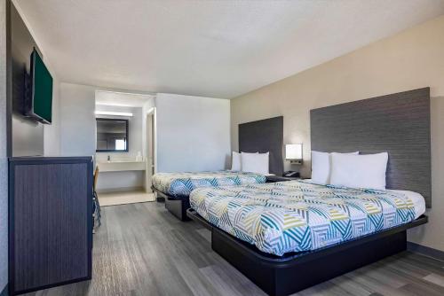 a hotel room with two beds and a television at Motel 6 Lake Charles, LA in Lake Charles