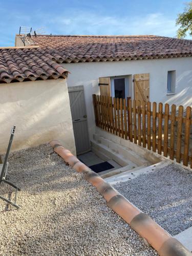 une maison avec une clôture en bois à côté d'une maison dans l'établissement Studio à la campagne, à La Tour-dʼAigues