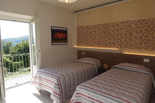 two beds in a room with a window at La Foresteria della Beppa in Zeri