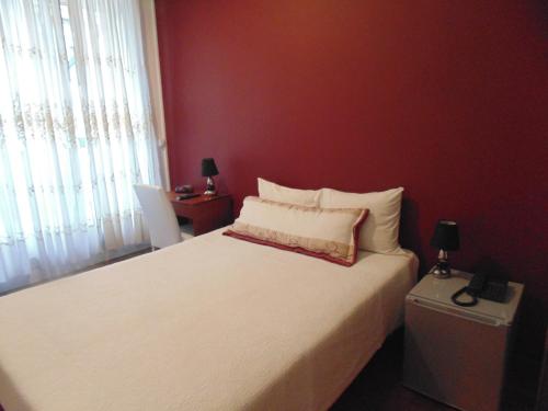 a bedroom with a white bed with a red wall at Hotel Porto Rico in Porto