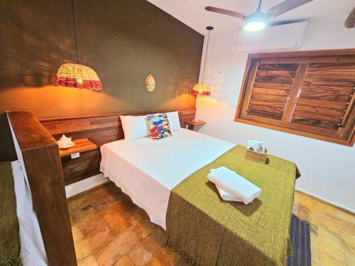 a bedroom with a bed with a table and a window at Chalés Mahalo J - Pontal de Maceió - Fortim in Fortim