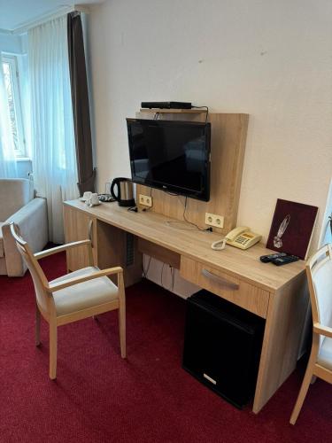 a hotel room with a desk with a television and two chairs at S und B Apartments Weingarten in Weingarten