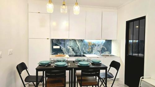 a kitchen with a black table and chairs in a room at Temple Marais 1 in Paris