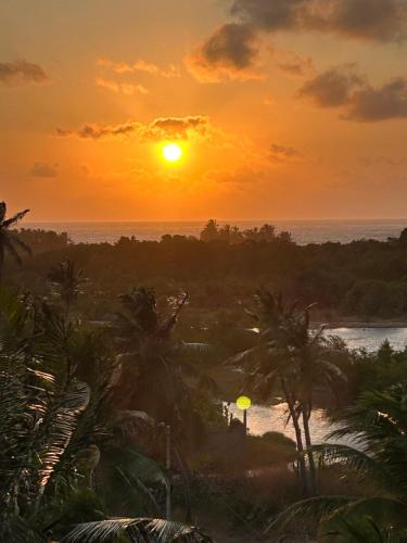 a sunset over the ocean with palm trees and a river at Casa Bela Vida in Fortim