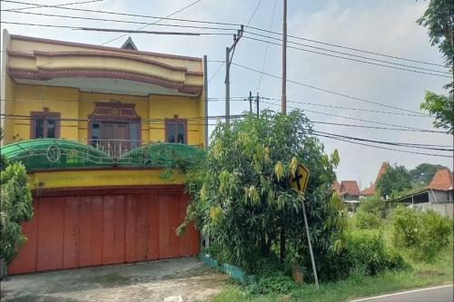 a yellow house with a red garage at Hotel O Setia Budi Guest House 2 in Sragen