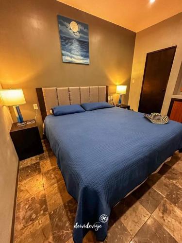 a bedroom with a large blue bed with two lamps at Residencial Edzna in Campeche