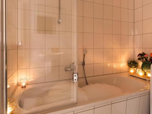 a bath tub in a bathroom with a shower at Schlosskönig - Modernes & zentrales Apartment mit Balkon und Arbeitsplatz in Schwerin